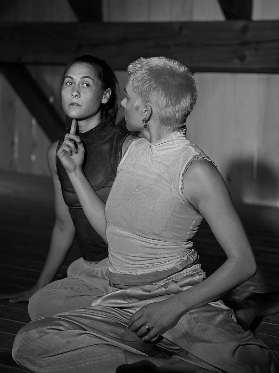 Two RUBBISH dancers in a timber-framed studio, one gesturing toward the other's chin