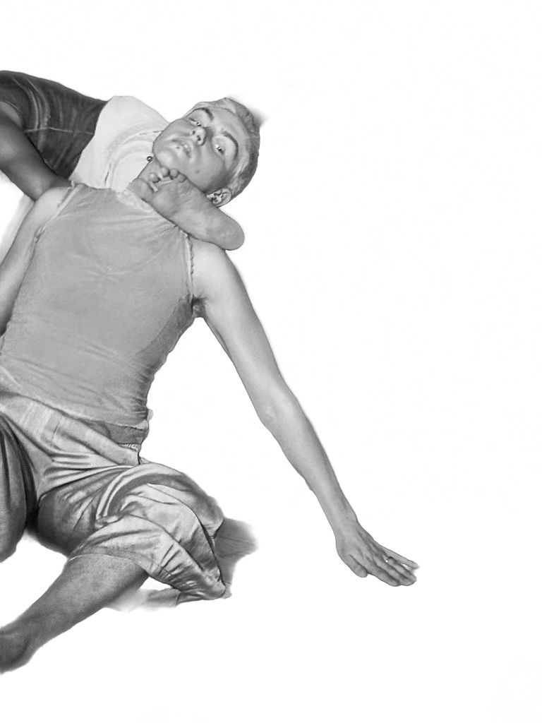 A dancer reclining mid-fall with a second dancer's foot resting at their neck